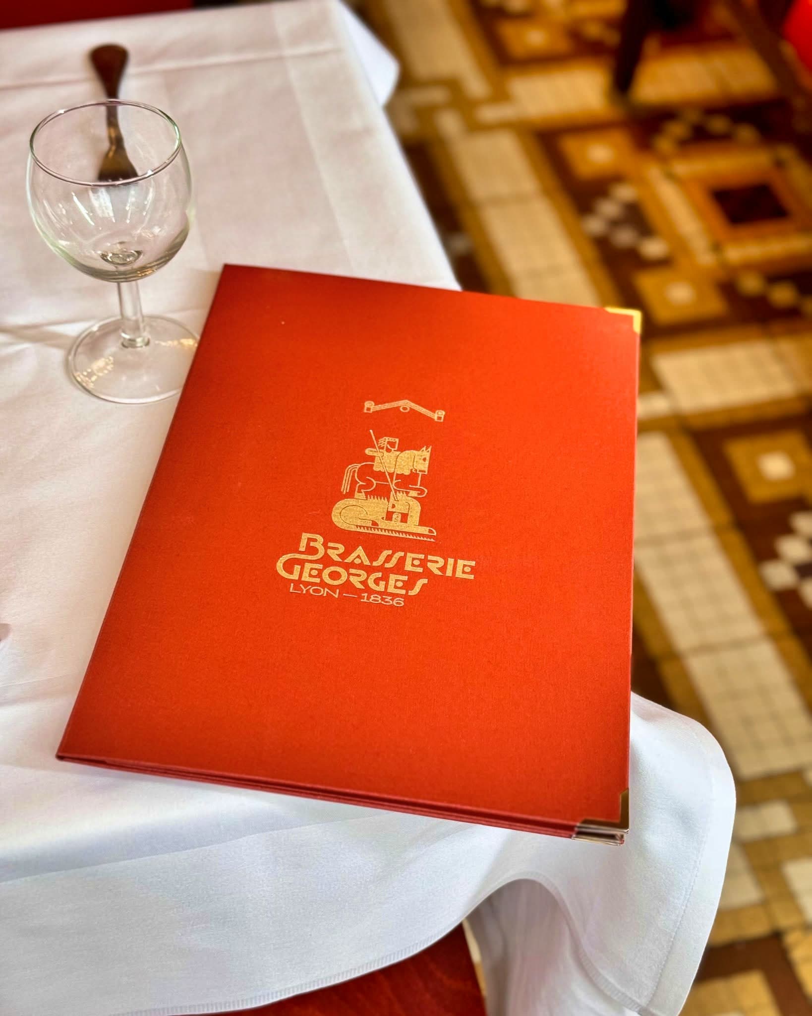 La carte de la Brasserie Georges, son emblème doré « Brasserie Georges, Lyon — 1836 » sur la couverture rouge