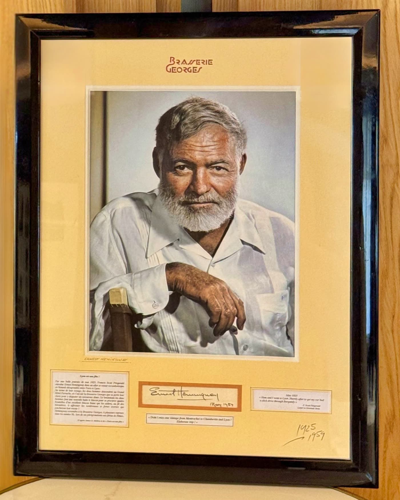 Portrait encadré d'Ernest Hemingway avec plaque commémorative accroché à un mur en bois — Brasserie Georges
