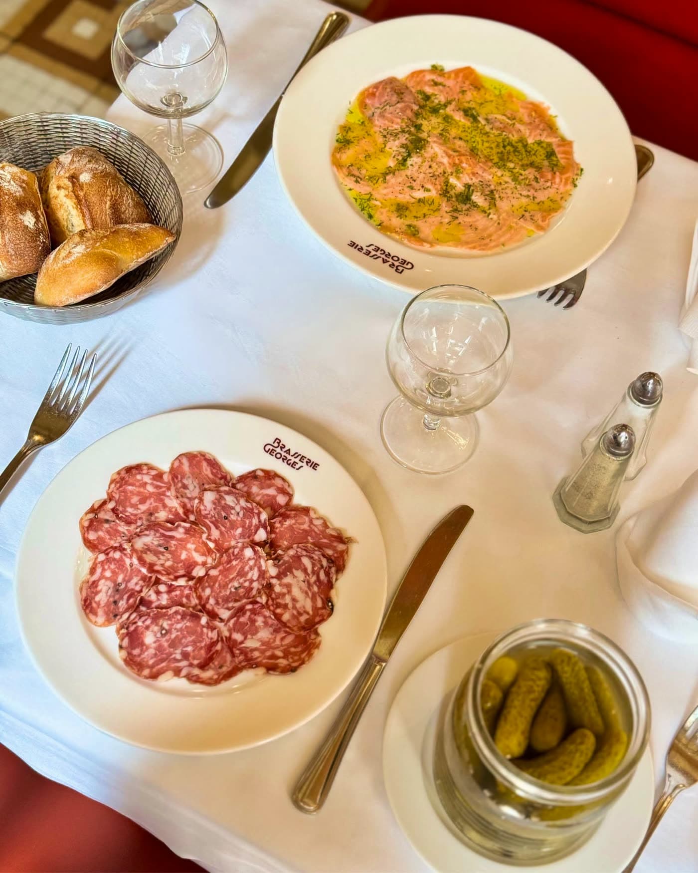 Vue de dessus d'une assiette de charcuterie et d'un carpaccio de saumon, pain et cornichons — Brasserie Georges