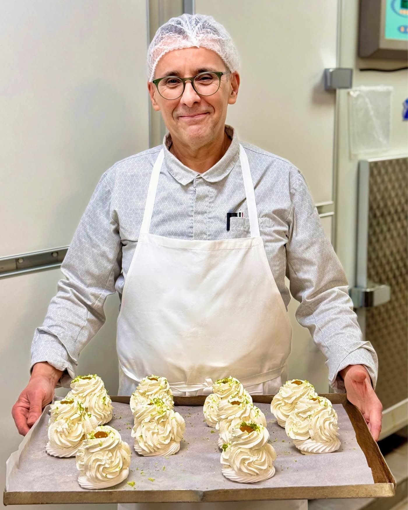 Pâtissier en charlotte tient un plateau de coques de meringue pistache — Brasserie Georges
