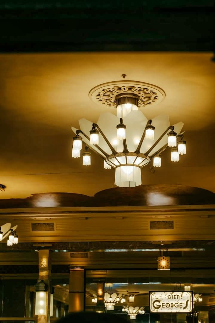 Lustre Art déco au plafond doré avec enseigne Biere Georges visible en bas — Brasserie Georges