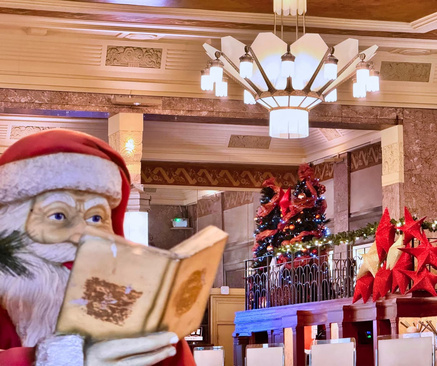 Statue de Père Noël lisant un livre devant décor de Noël en salle — Brasserie Georges