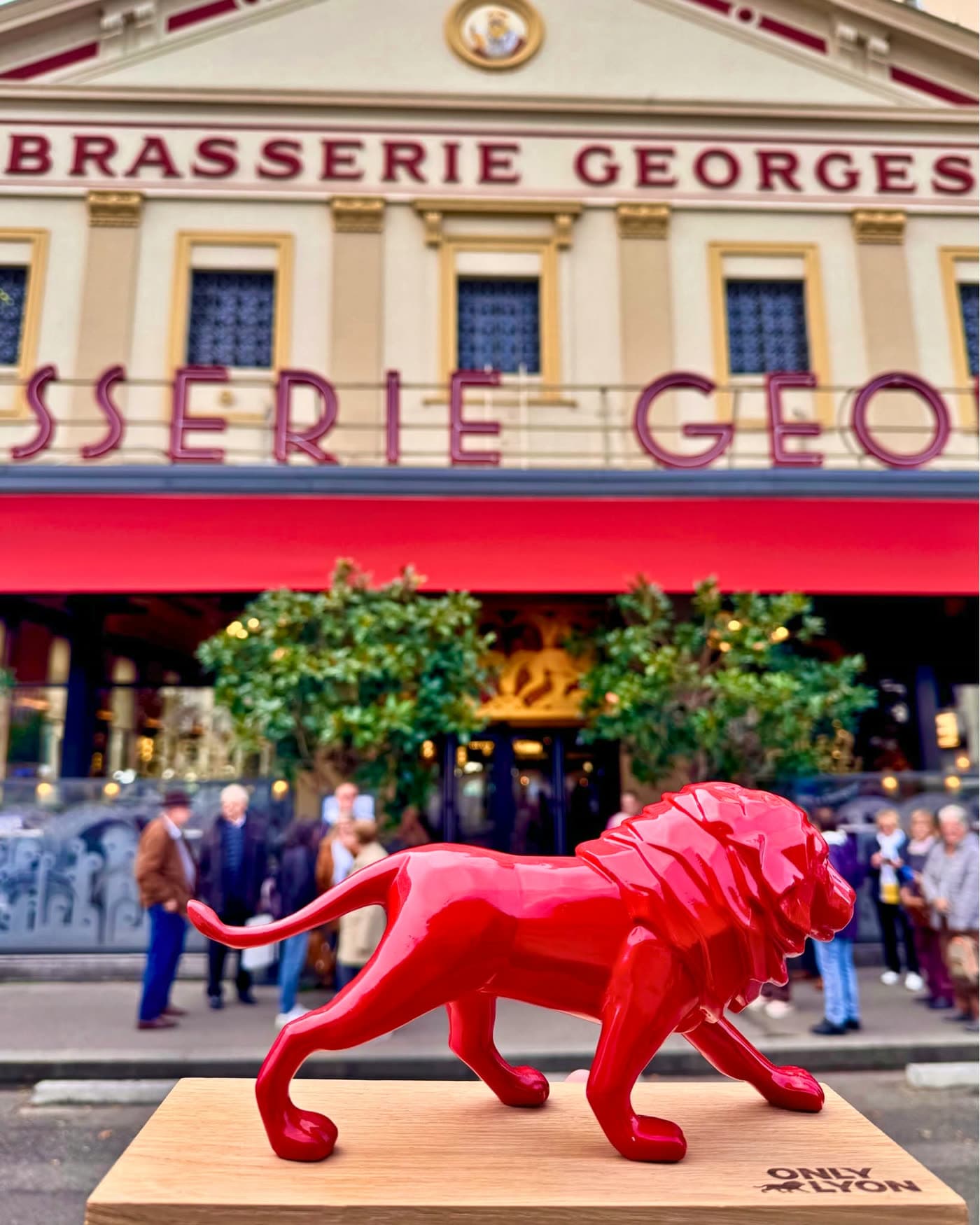 Statue de lion rouge OnlyLyon posée devant la façade de la Brasserie Georges