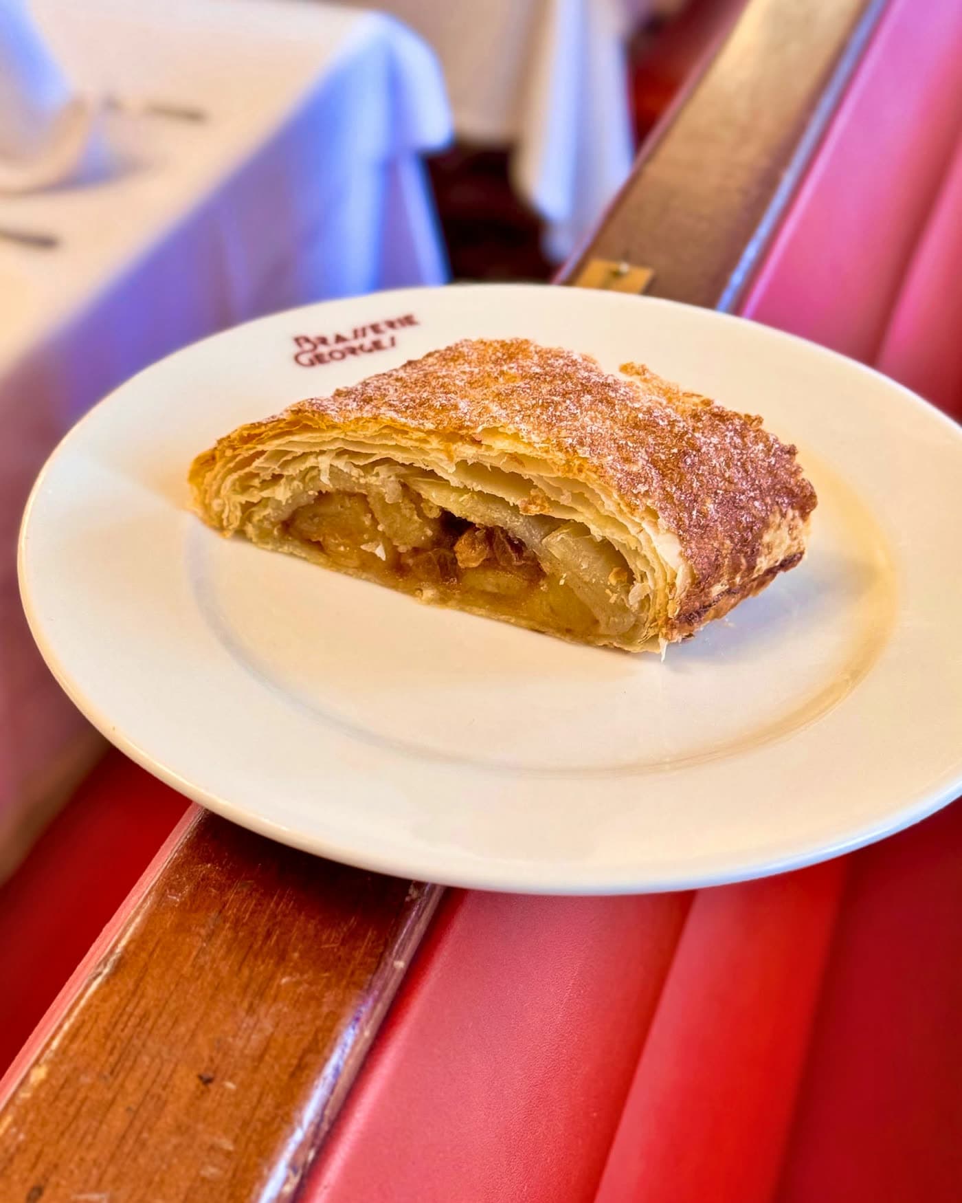 Chausson aux pommes sur assiette posée sur une banquette rouge — Brasserie Georges