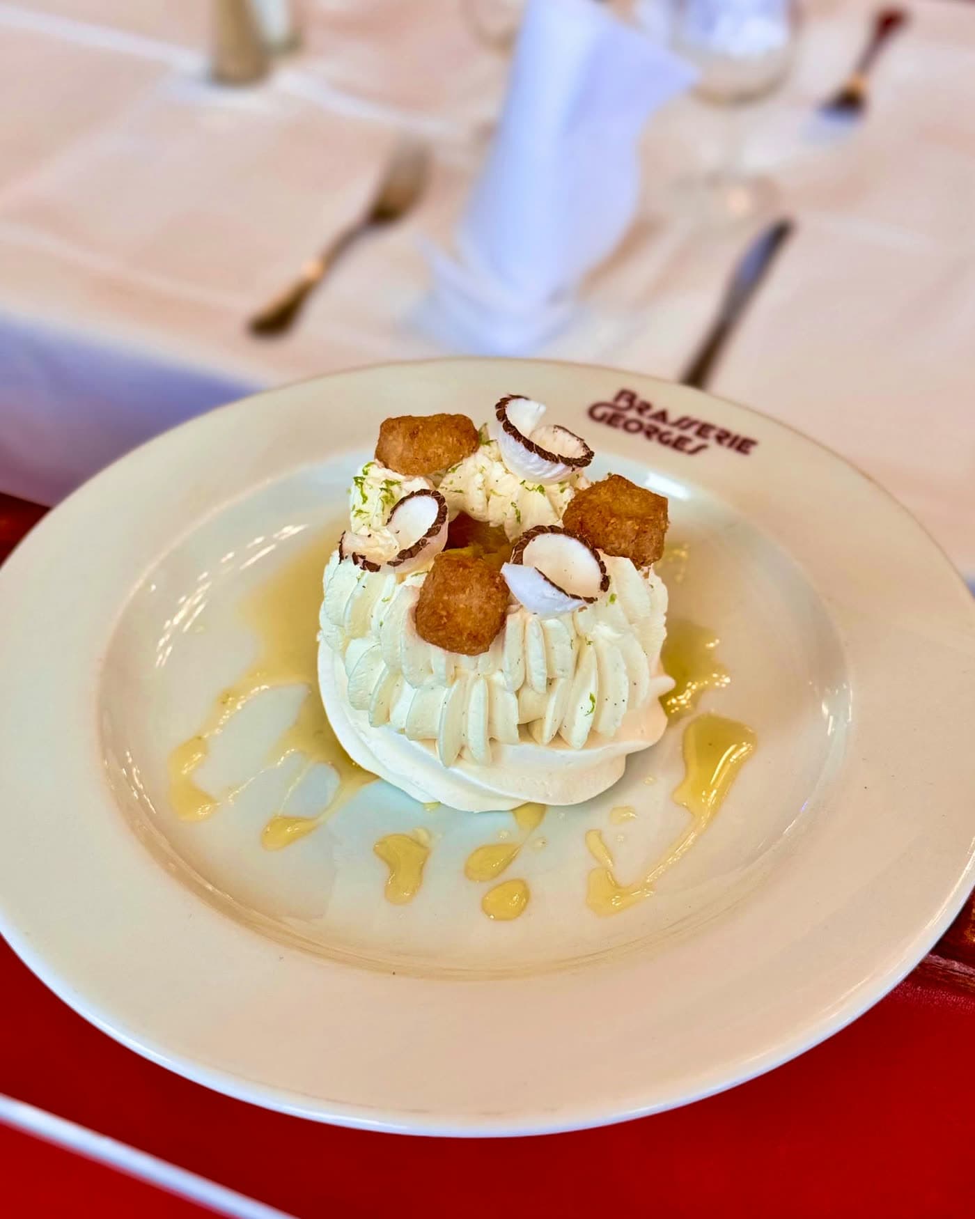 Dessert glacé nappé de crème fouettée avec tuiles croquantes, table dressée en fond — Brasserie Georges