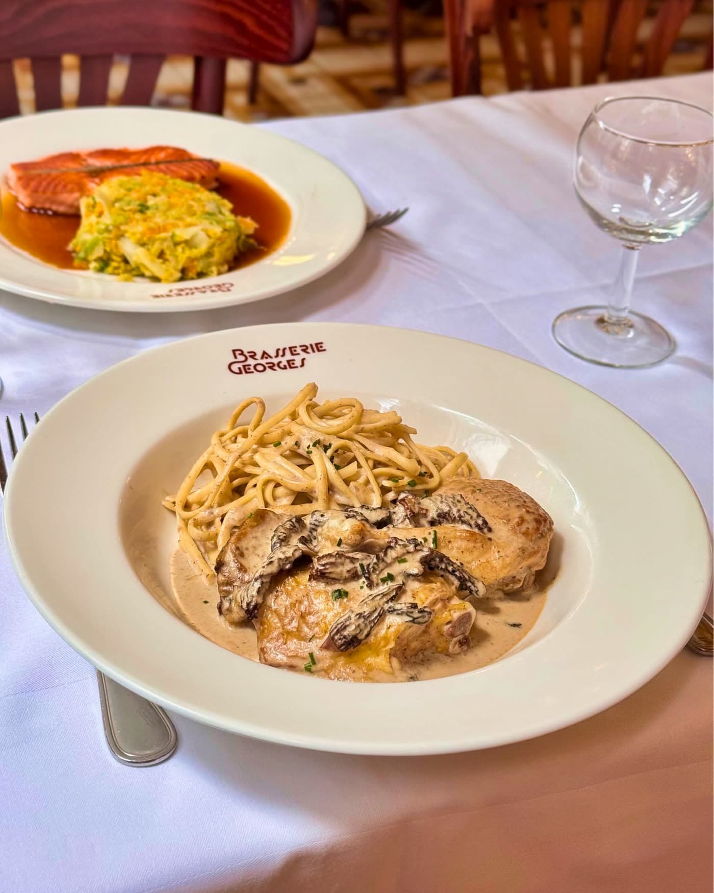 Volaille sauce aux morilles avec tagliatelles, assiette de saumon floue en arrière-plan — Brasserie Georges