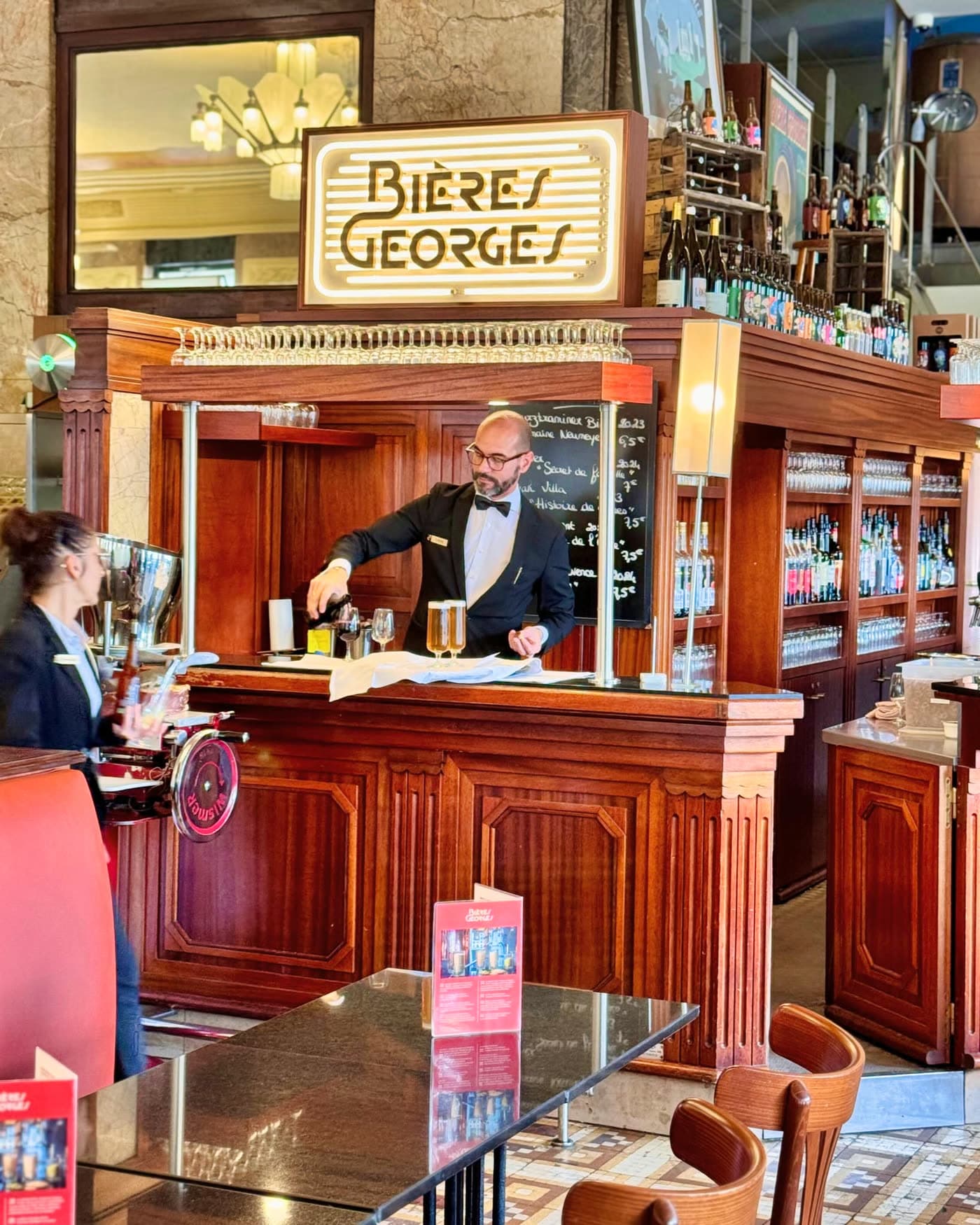 Comptoir en bois Bières Georges avec enseigne lumineuse et barman servant un verre — Brasserie Georges