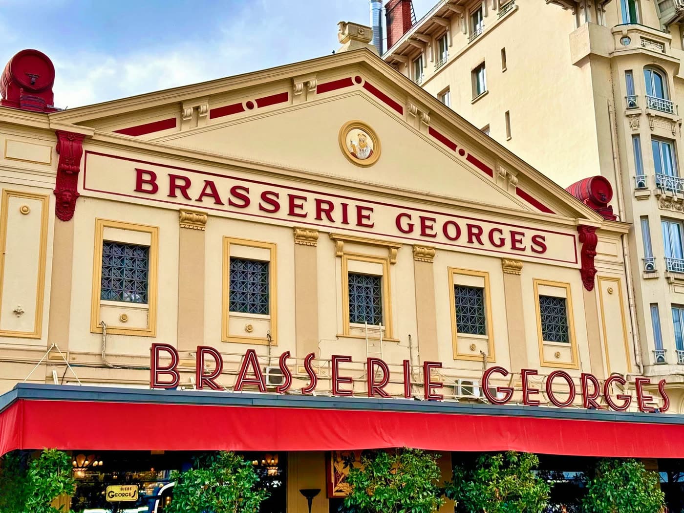 Façade et auvent rouge Brasserie Georges vus de près, lettrage doré sur le pignon