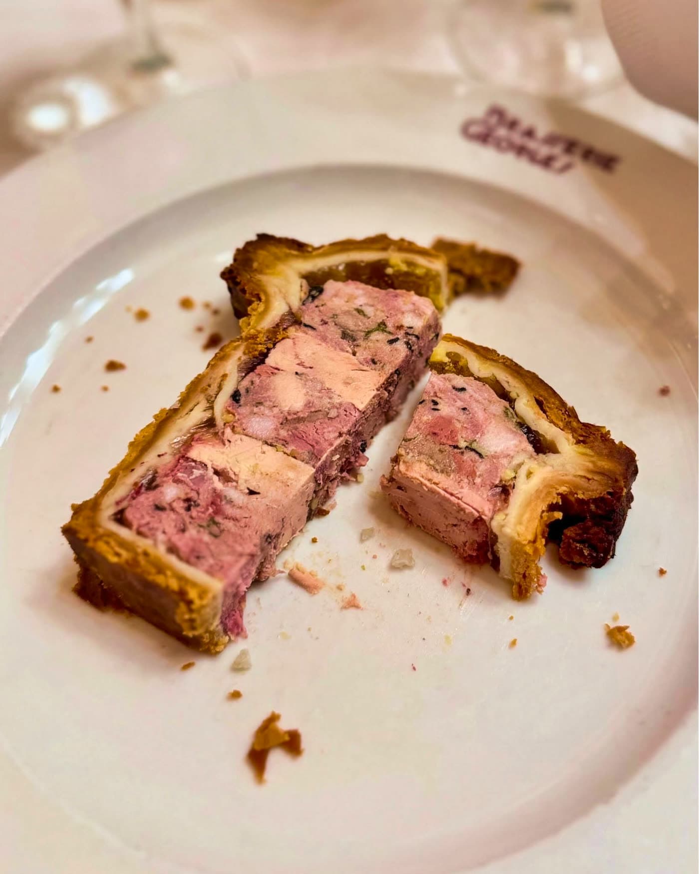 Pâté en croûte tranché en gros plan avec farce rosée, assiette logo restaurant — Brasserie Georges