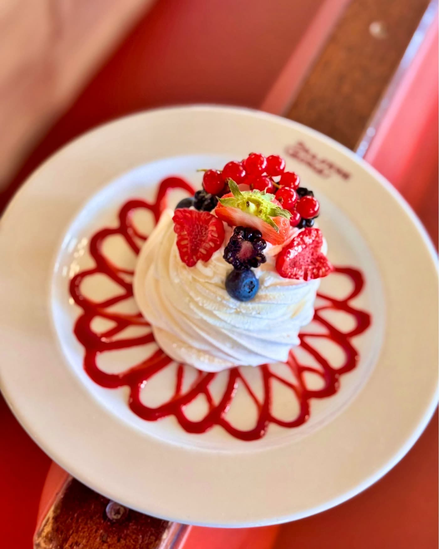 Meringue chantilly aux fruits rouges sur assiette décorée d'un coulis en spirale — Brasserie Georges