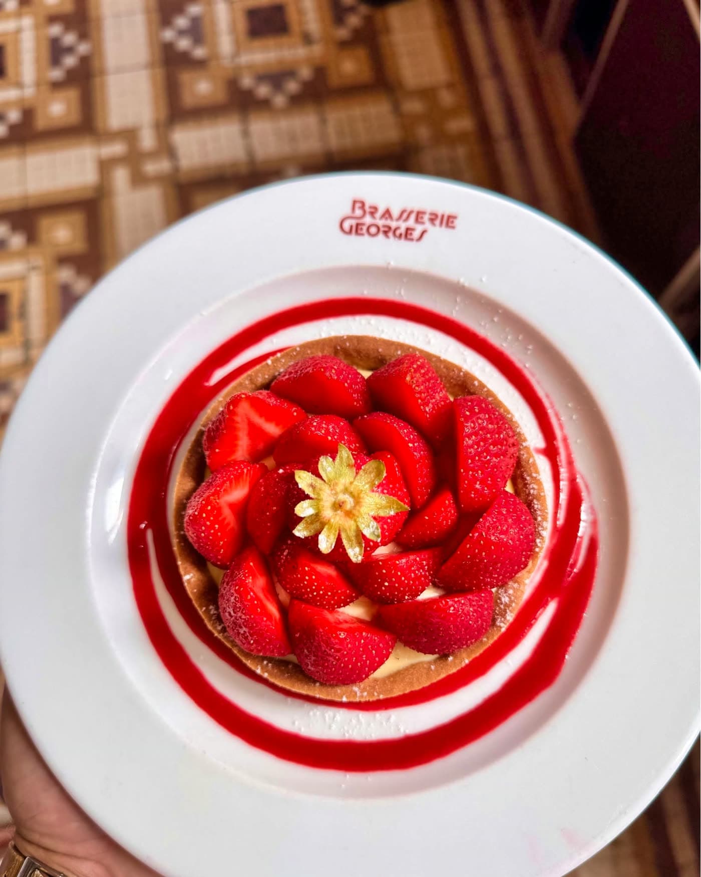 Tarte aux fraises fraîches vue de dessus avec coulis en spirale, assiette logo restaurant — Brasserie Georges