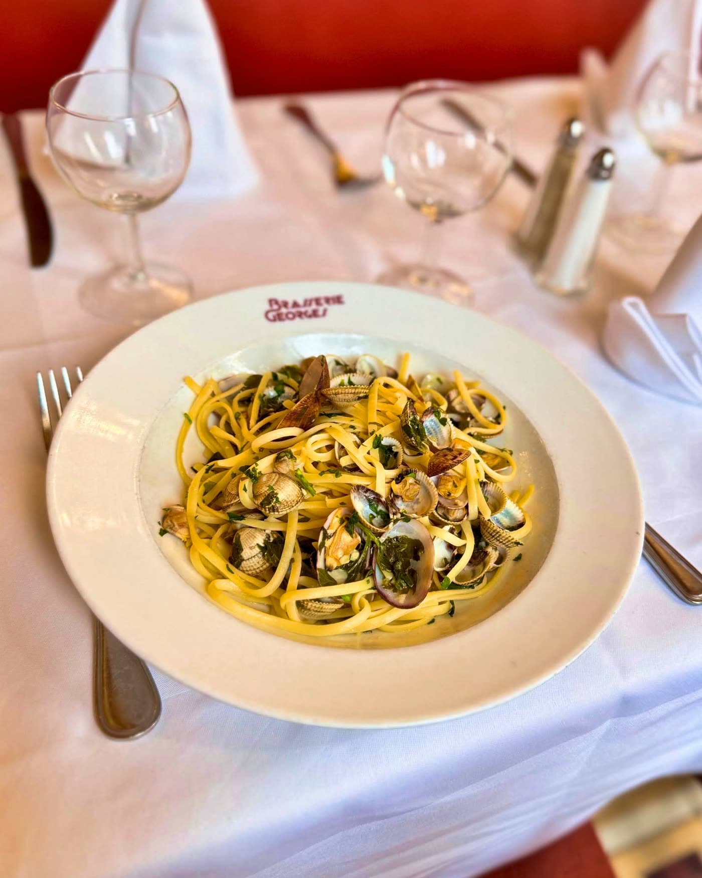 Linguine aux palourdes et persillade dans assiette creuse sur table dressée — Brasserie Georges