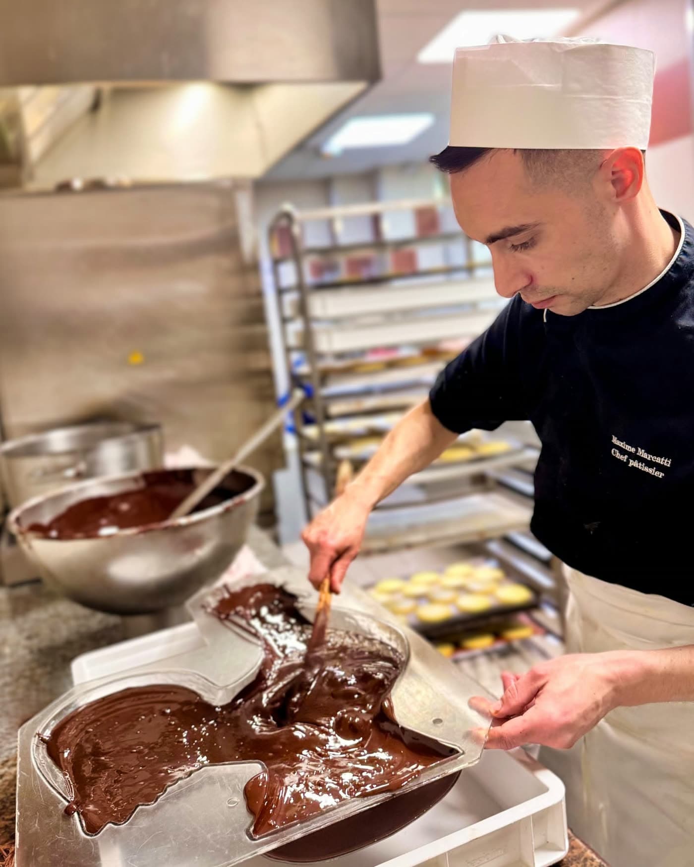 Pâtissier en toque garnissant un moule à chocolat en forme d'animal — Brasserie Georges