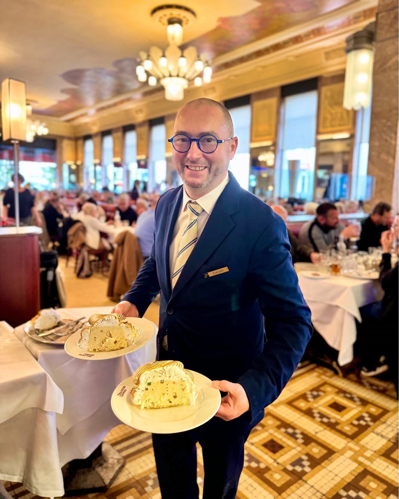 Maître d'hôtel en costume présentant deux profiteroles/omelettes norvégiennes dans la salle — Brasserie Georges
