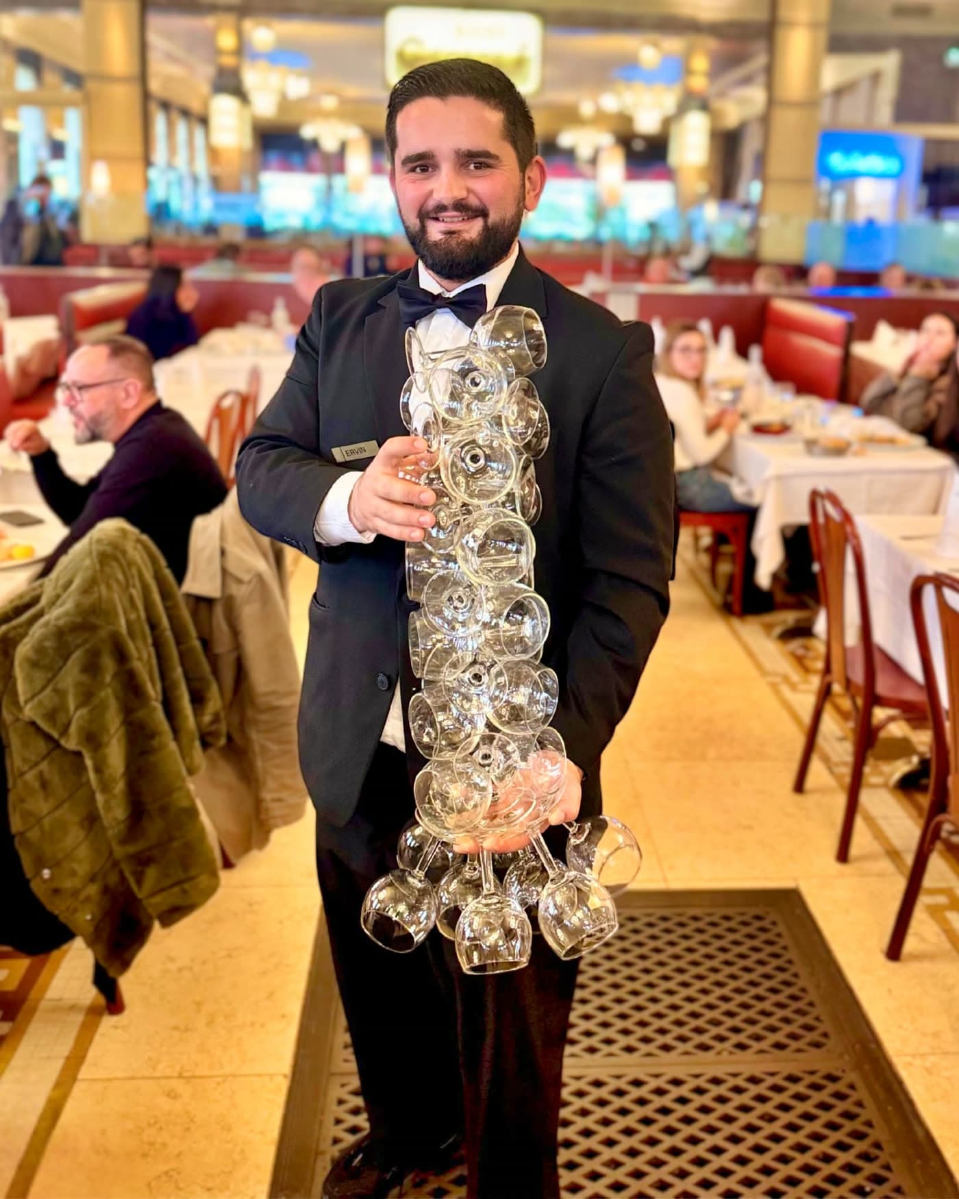 Sommelier en costume portant une pile impressionnante de verres à vin empilés — Brasserie Georges