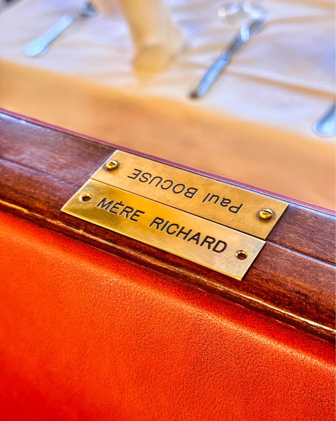 Plaque en laiton gravée Mère Richard Paul Bocuse fixée sur banquette bois — Brasserie Georges