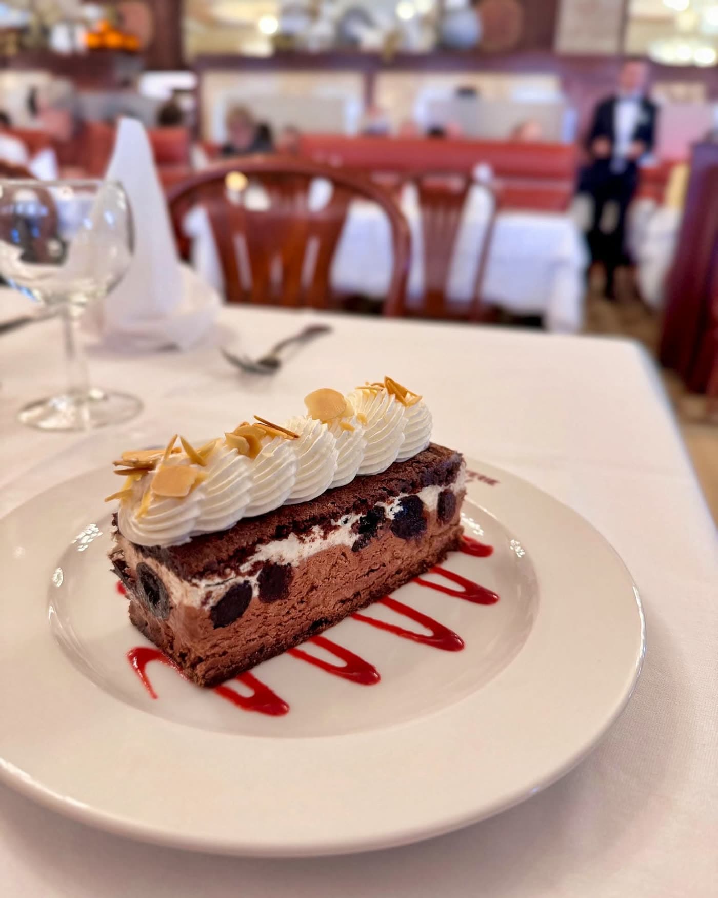 Part de gâteau chocolat crème fruits rouges sur assiette blanche en salle — Brasserie Georges