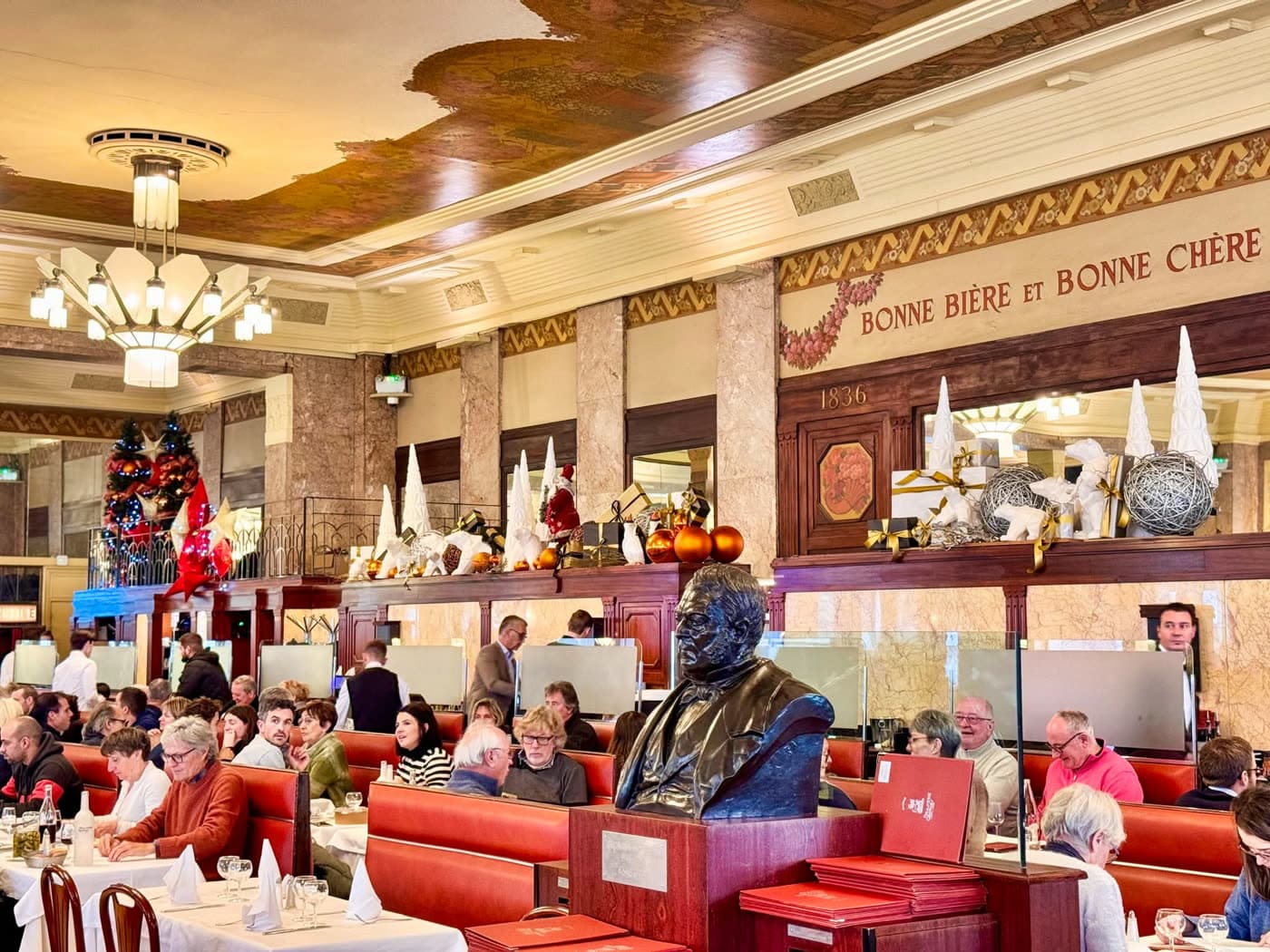 Vue d'ensemble de la salle Art déco avec plafond peint, buste, sapins de Noël et nombreux clients attablés — Brasserie Georges