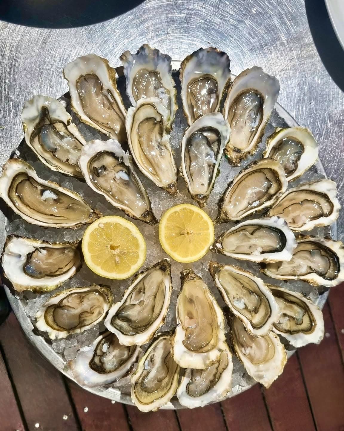 Plateau d'huîtres disposées en cercle sur glace avec deux demi-citrons au centre, vue de dessus — Brasserie Georges