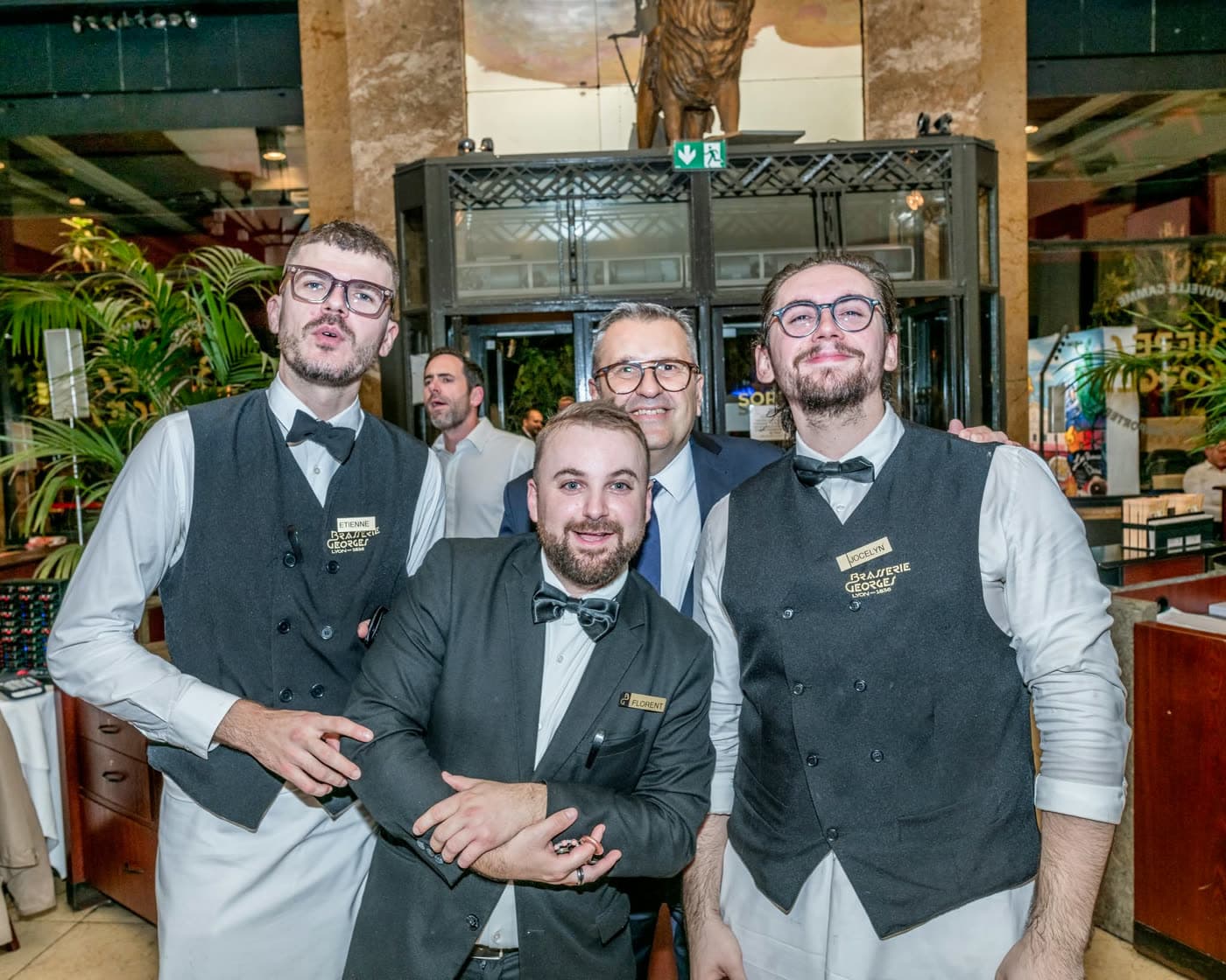Quatre membres du personnel en tenue chic posent en souriant dans le hall — Brasserie Georges