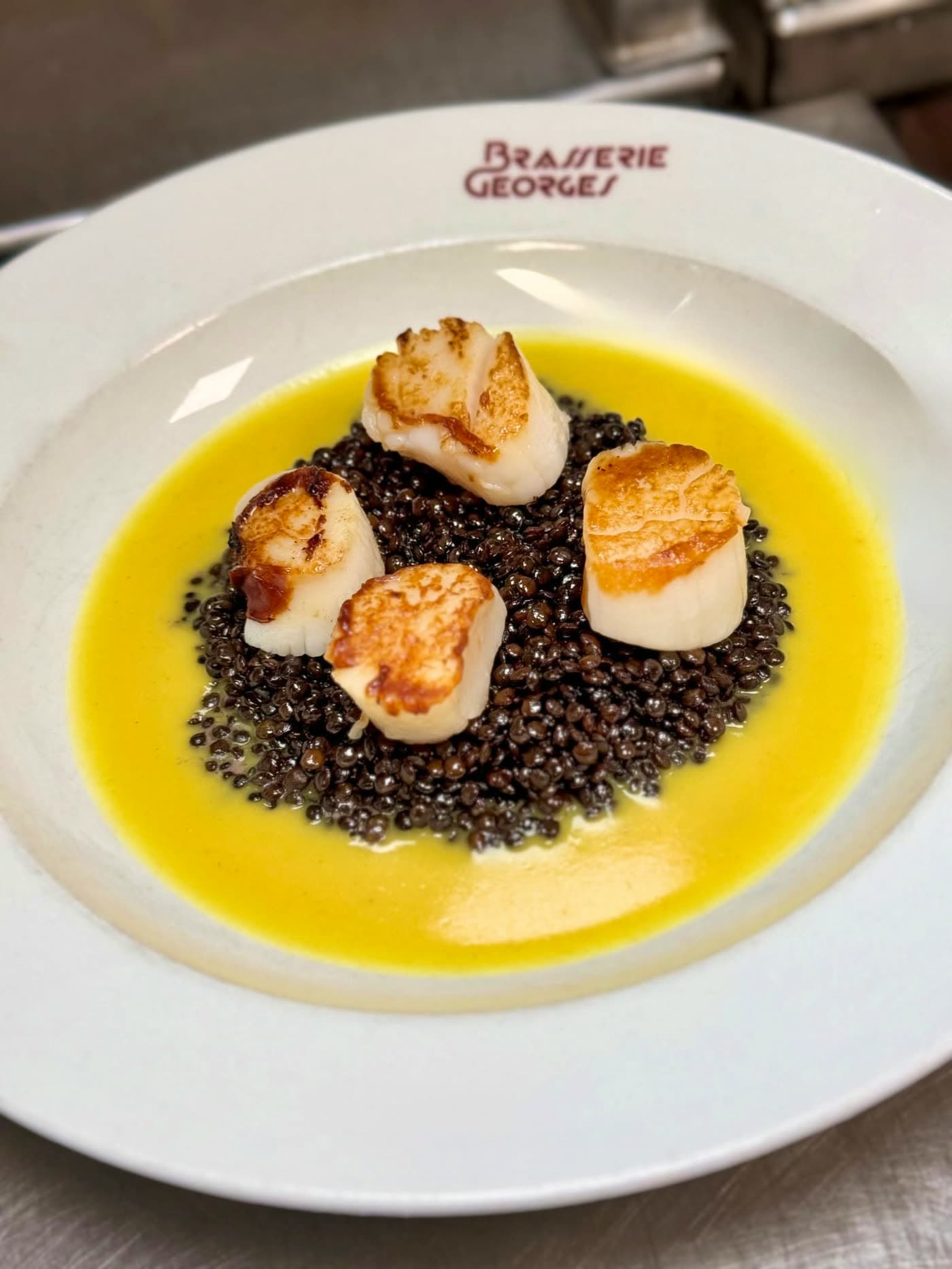 Quatre noix de saint-jacques poêlées sur lentilles noires, sauce au beurre jaune — Brasserie Georges