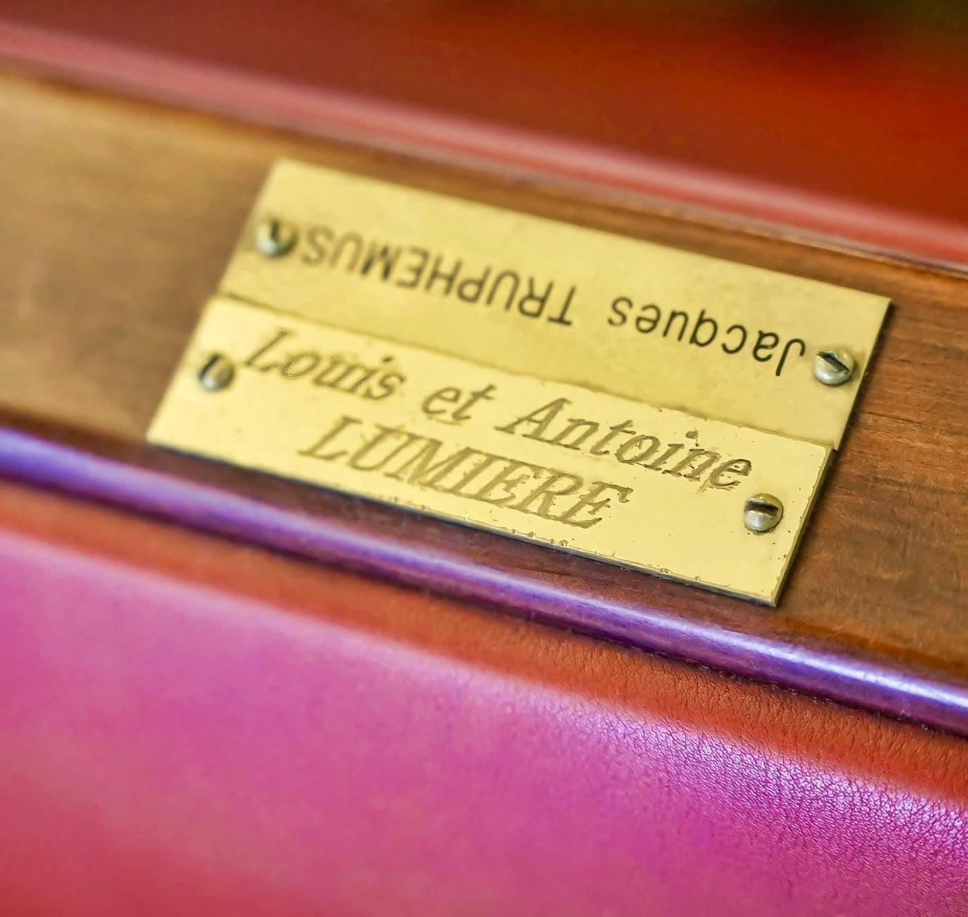 Plaques en laiton nommant Louis et Antoine Lumière sur une banquette, détail patrimonial — Brasserie Georges