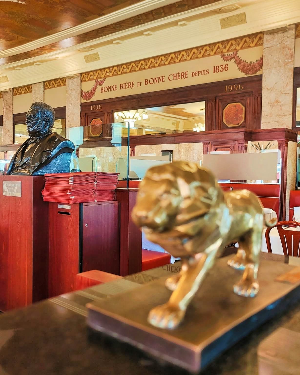 Buste du fondateur et statue de lion doré sur comptoir, fresque « depuis 1836 » — Brasserie Georges