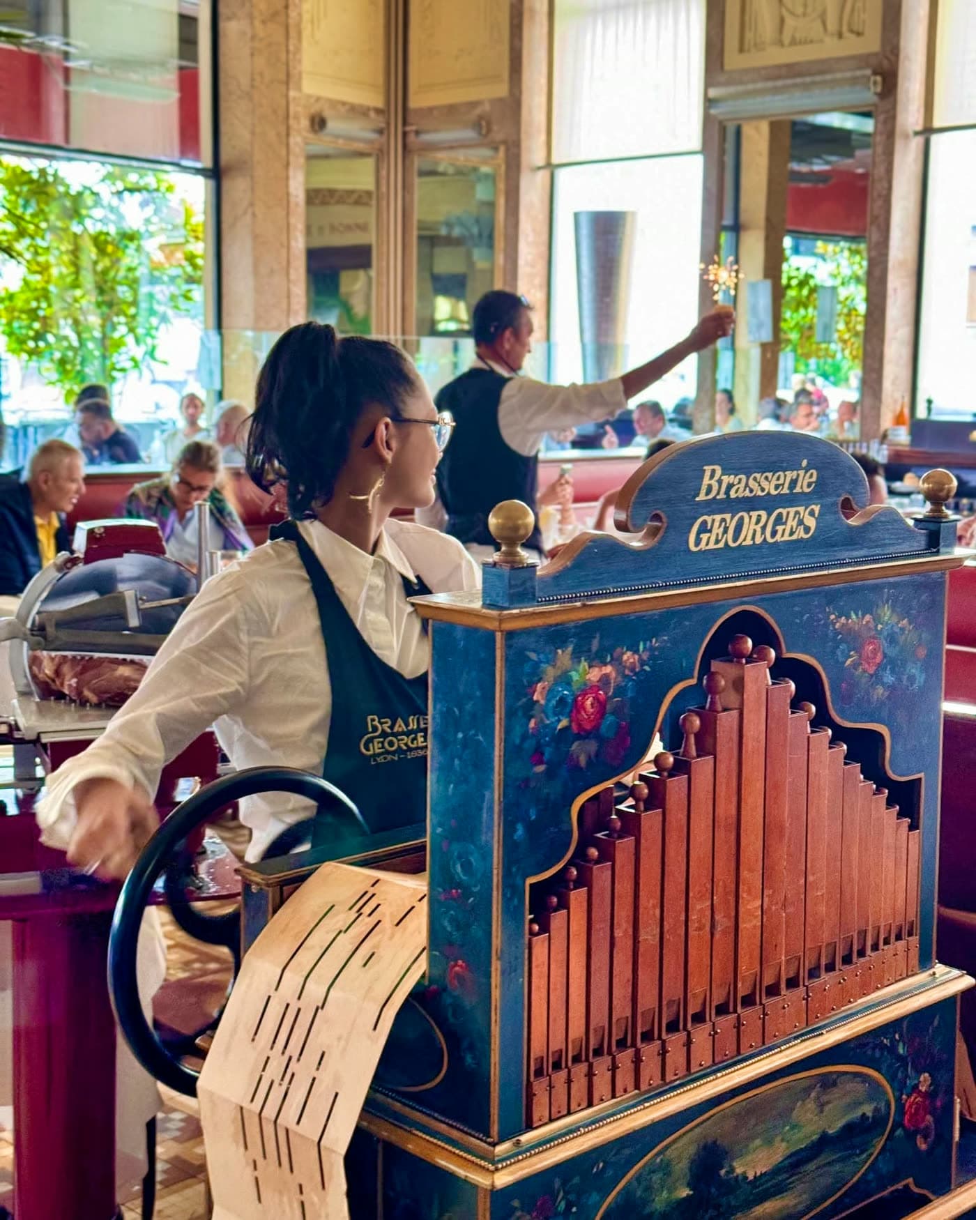 Orgue de barbarie siglé Brasserie Georges avec serveuse à proximité