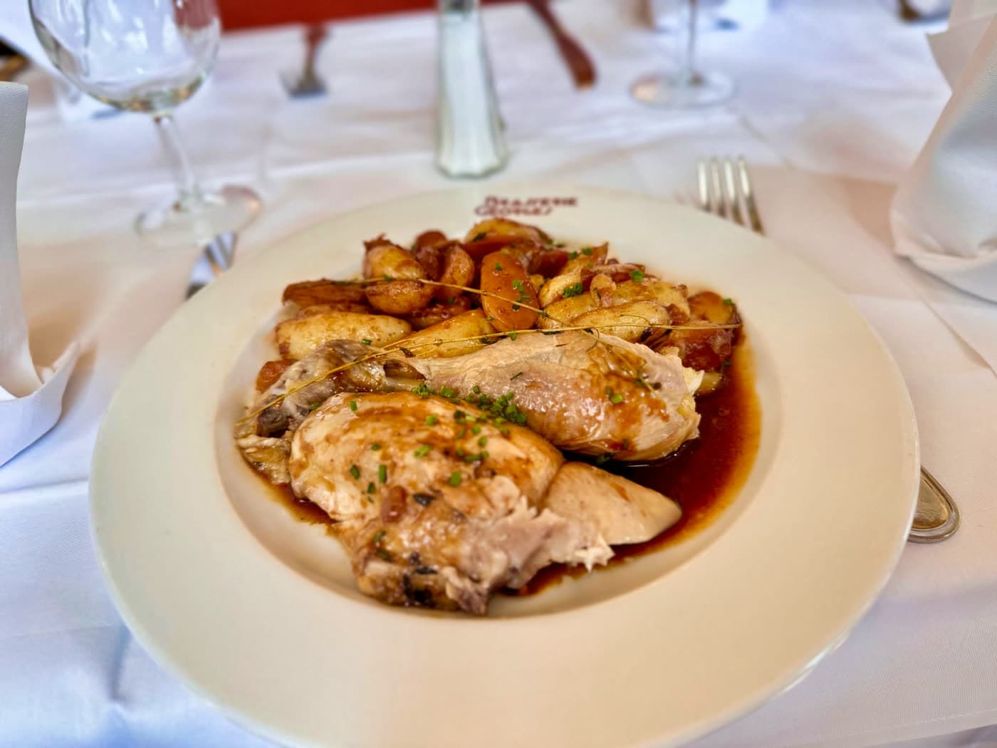 Volaille rôtie en sauce avec pommes de terre sur assiette blanche — Brasserie Georges