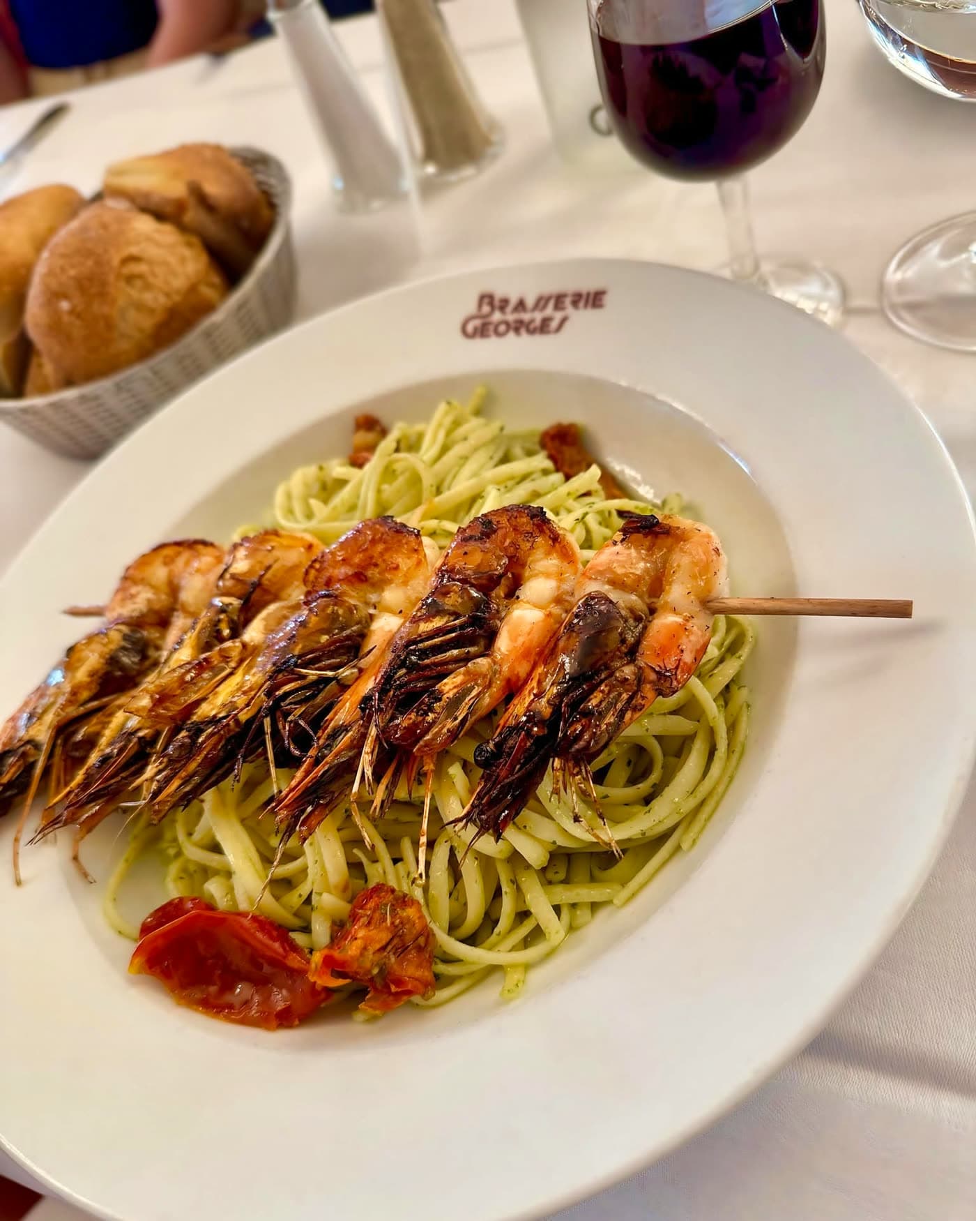 Brochette de gambas grillées sur tagliatelles vertes, panier de pain et vin — Brasserie Georges