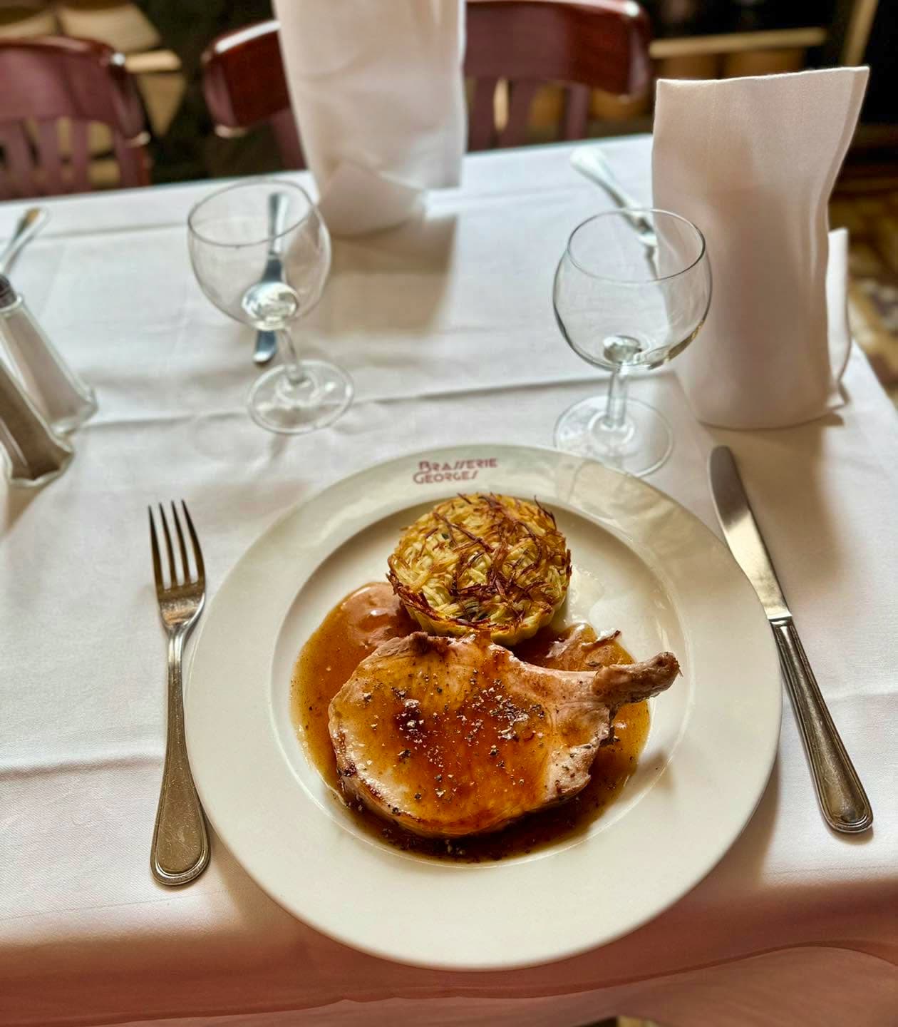 Volaille rôtie accompagnée d'un gratin, table dressée avec verres et serviettes pliées — Brasserie Georges
