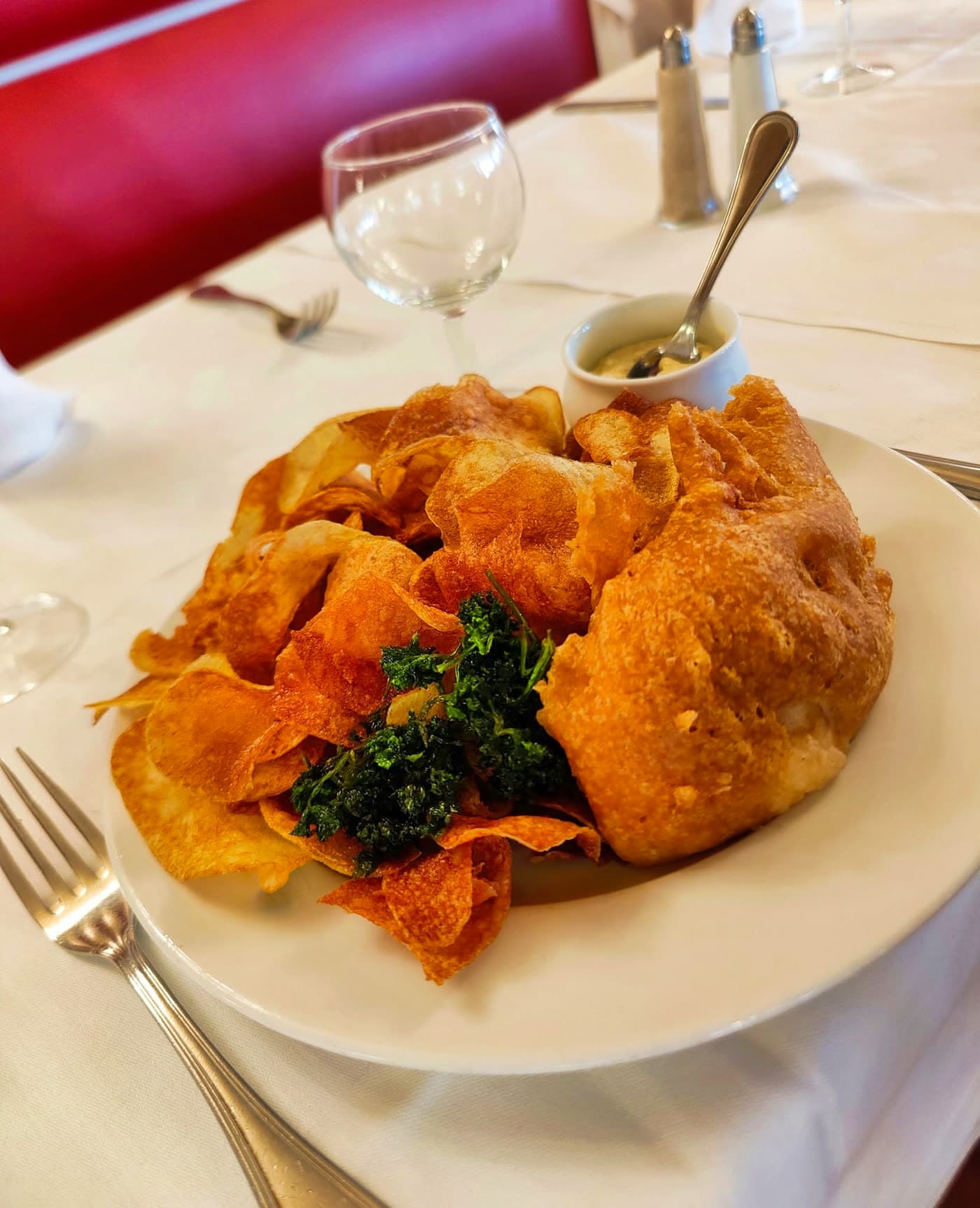 Beignet doré garni de chips et pousses vertes, nappe blanche, banquette rouge en fond — Brasserie Georges