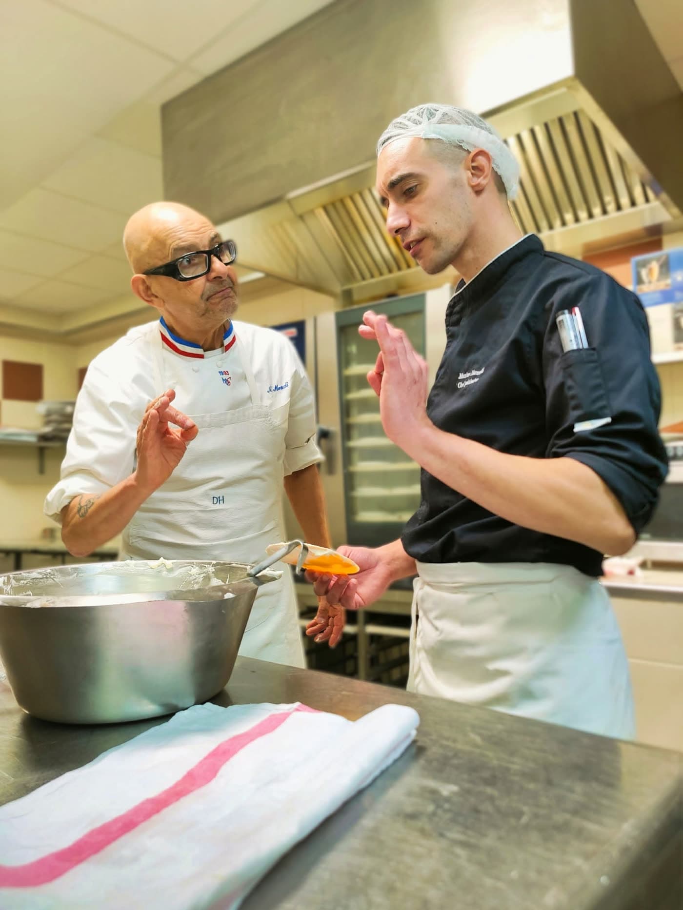 Pâtissier expérimenté guide un jeune commis lors d'une démonstration de dressage en cuisine — Brasserie Georges