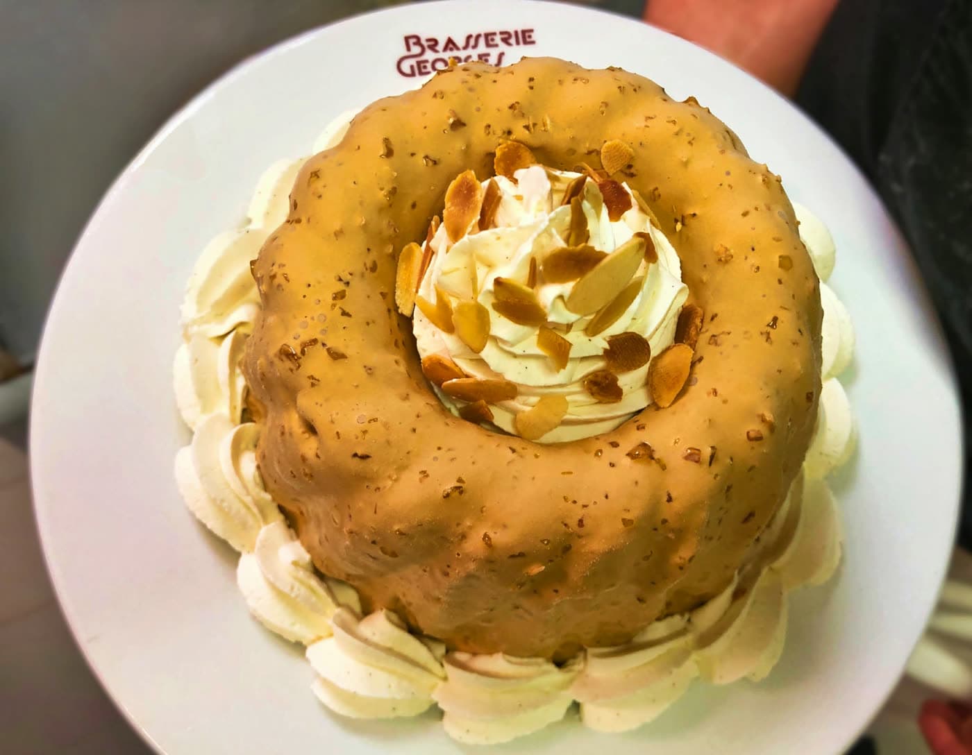 Gâteau rond glacé au caramel avec rosaces de chantilly et amandes effilées, assiette floquée — Brasserie Georges