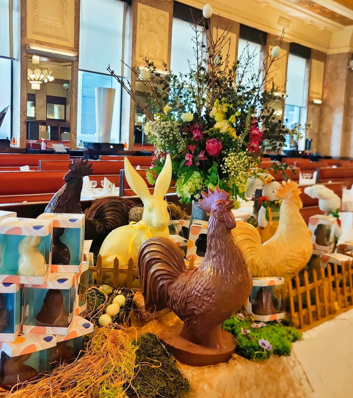 Décor de Pâques avec coqs et lapins en chocolat, bouquet de fleurs, boîtes cadeaux dans la salle — Brasserie Georges