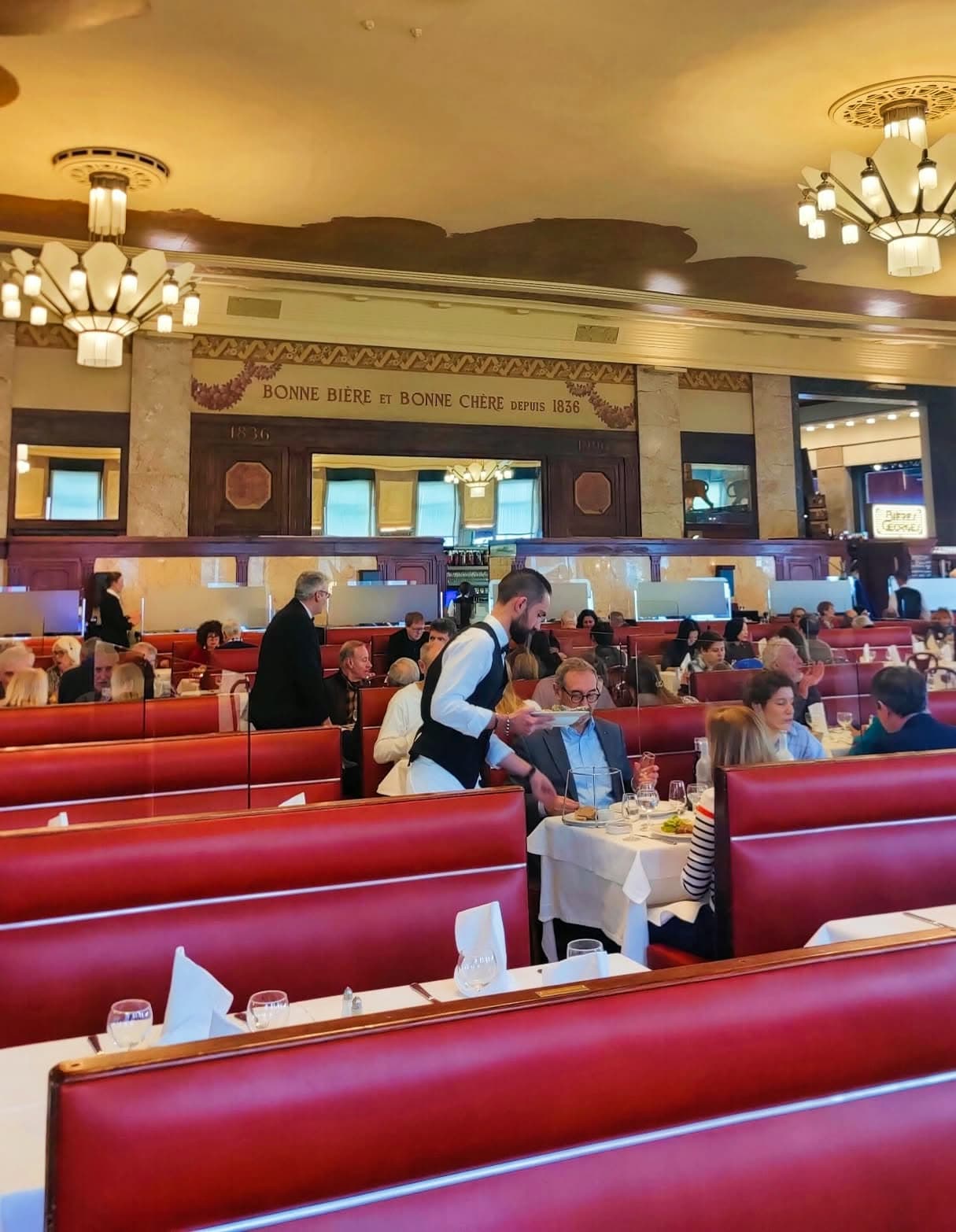 Vue de la grande salle Art déco avec banquettes rouges, tables dressées et clients attablés, frise « Bonne Bière et Bonne Chère » — Brasserie Georges