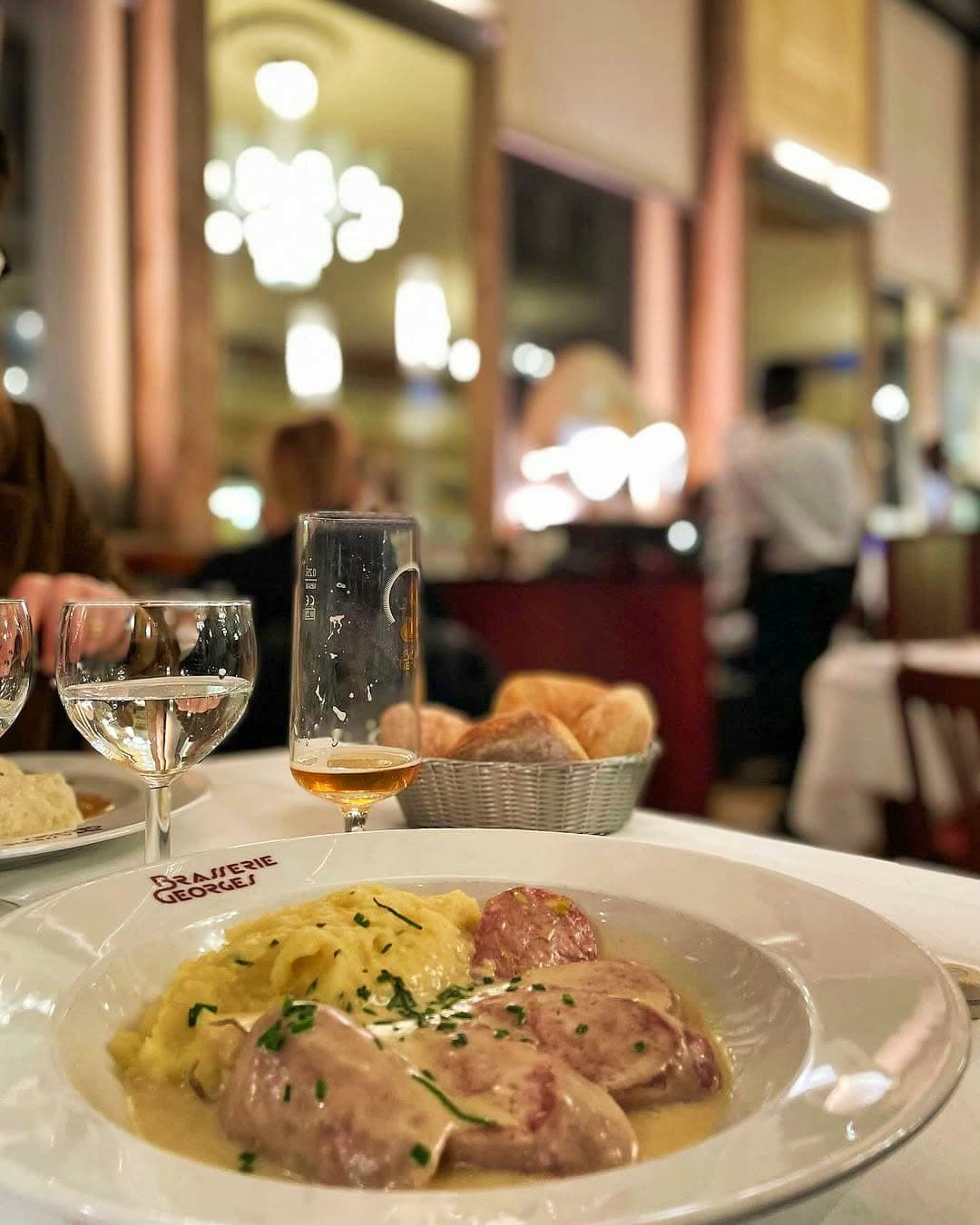 Assiette de choucroute royale sur table dressée, verres et pain, ambiance de soirée — Brasserie Georges