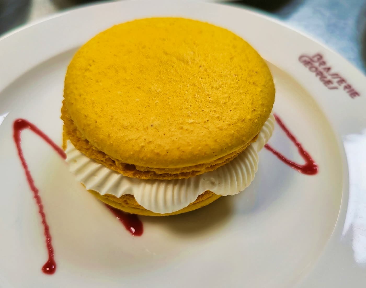 Macaron géant garni de crème, assiette frappée du logo Brasserie Georges