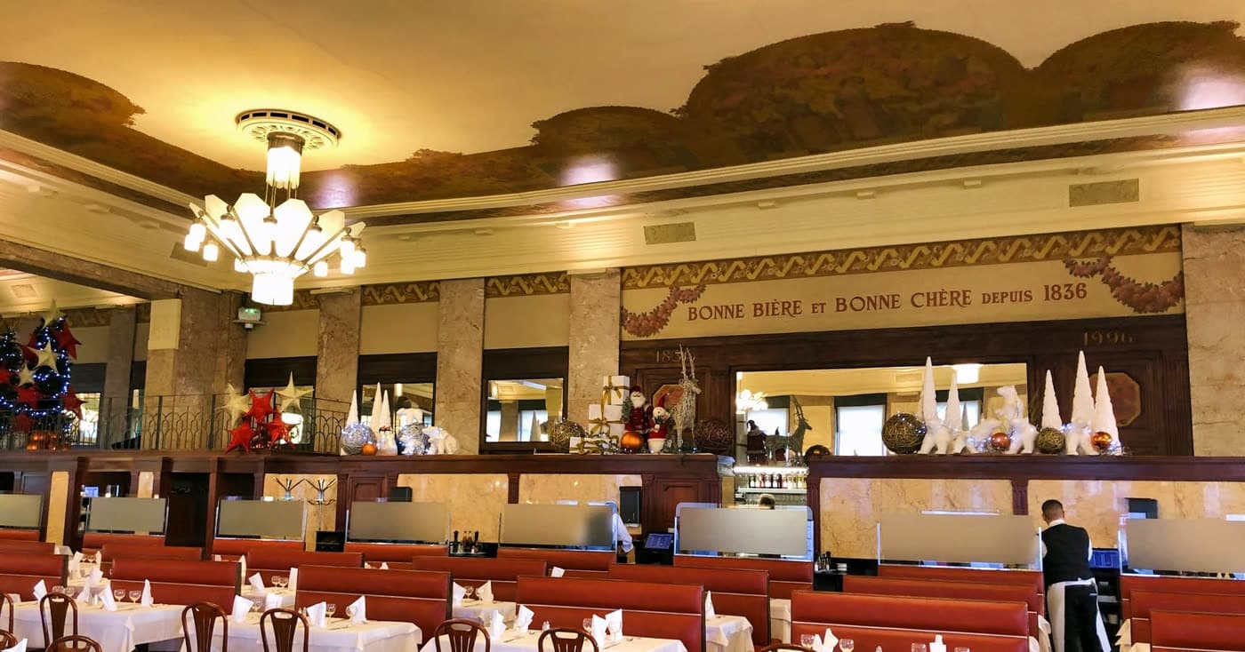 Vue de la salle avec plafond voûté doré, grand lustre, frise historique, tables dressées — Brasserie Georges