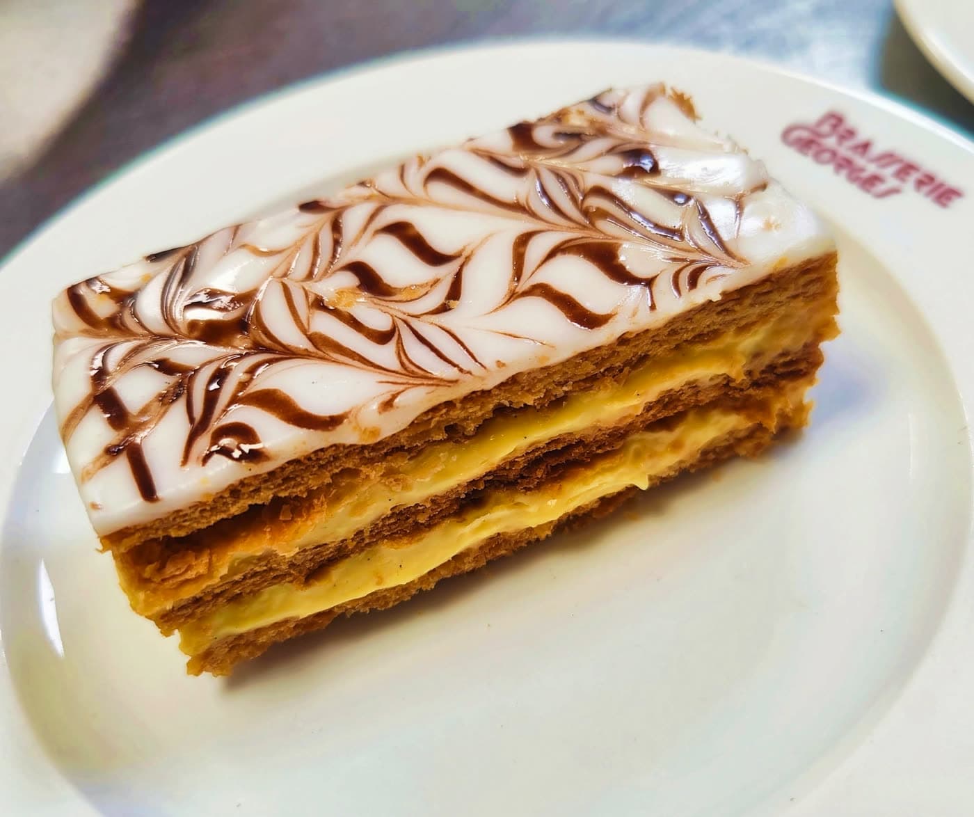 Mille-feuille au glaçage marbré sur assiette frappée du logo Brasserie Georges