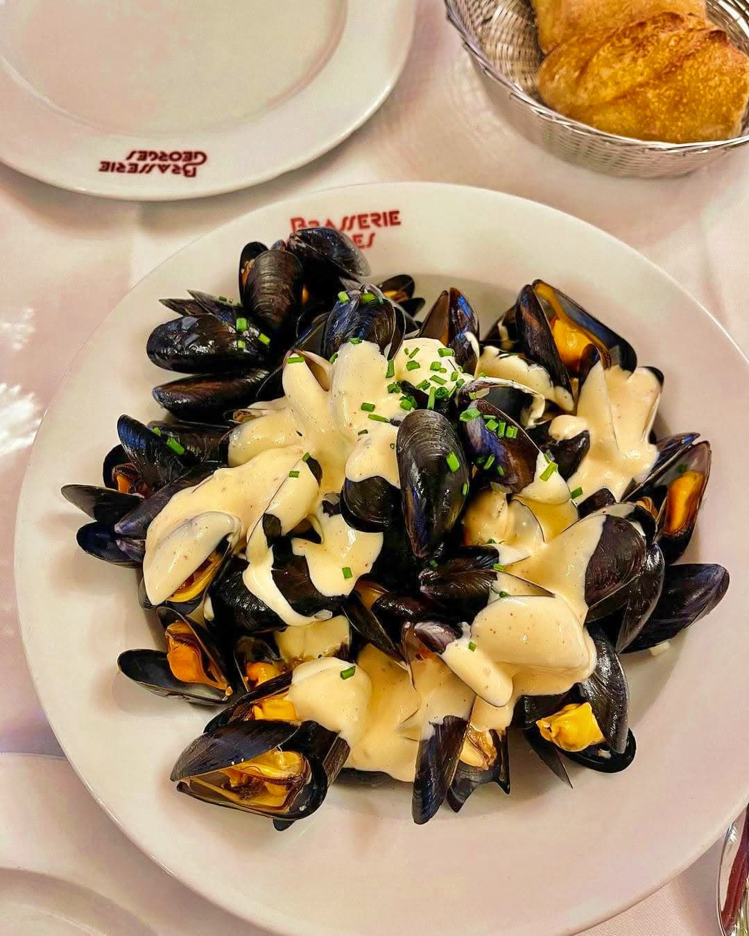 Moules marinière sauce crème vues de dessus, corbeille de pain à côté — Brasserie Georges