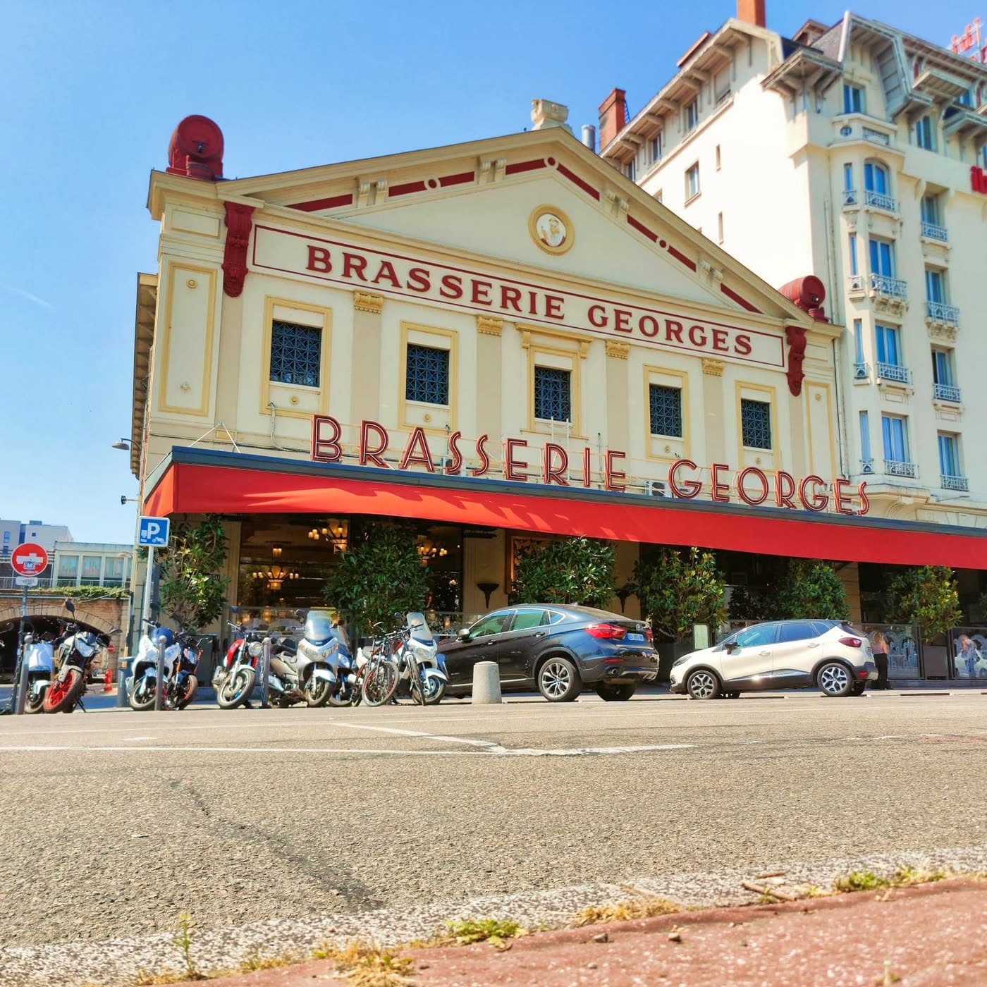 Façade de la brasserie sous ciel bleu, motos garées devant l'entrée — Brasserie Georges