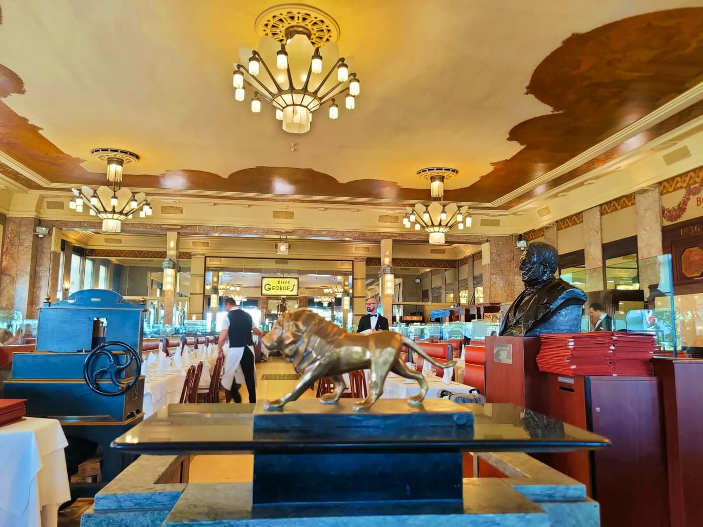 Salle avec lustres Art déco, buste en bronze et sculpture de chien — Brasserie Georges