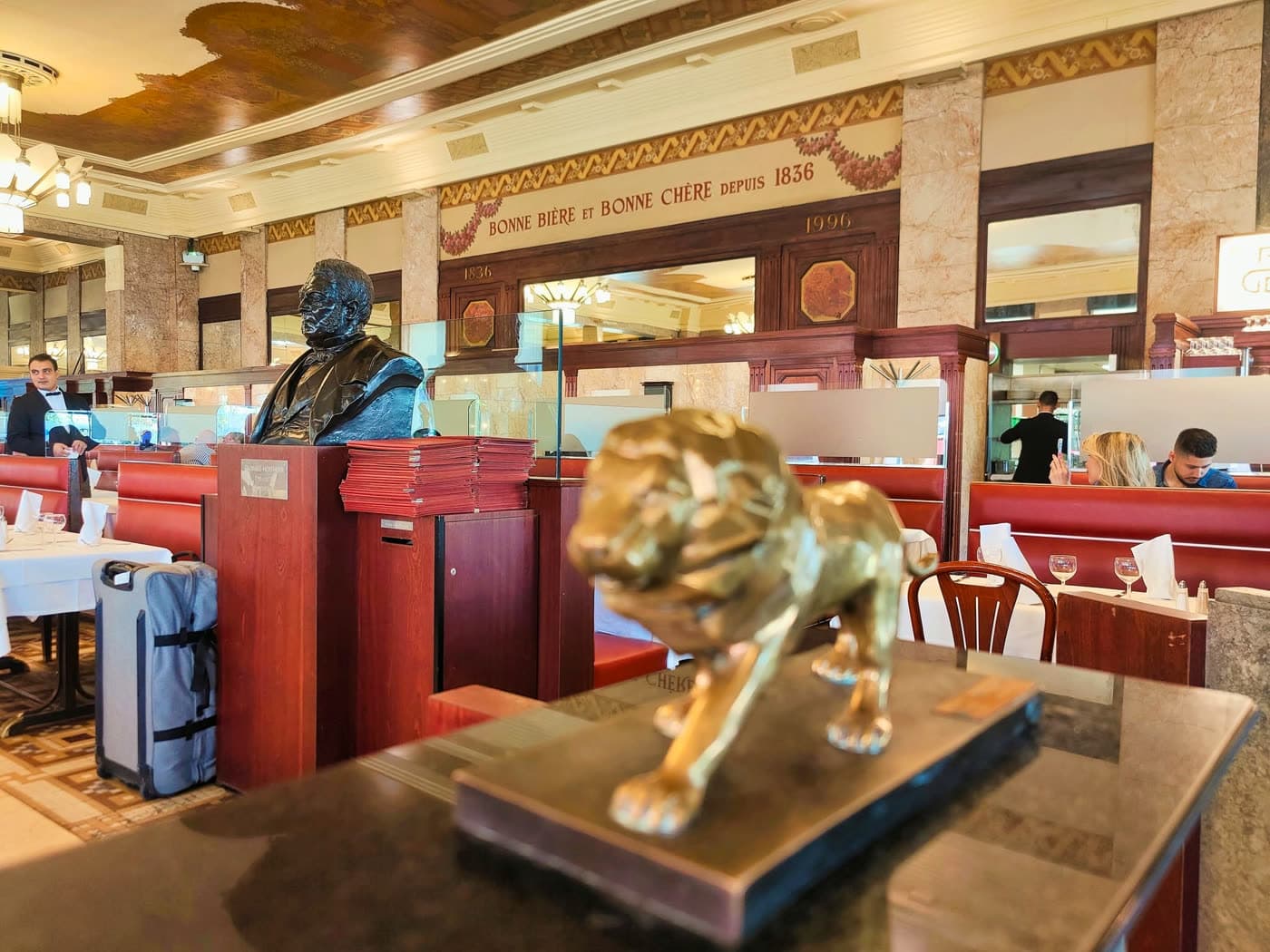Vue de la salle avec buste doré, statue de lion et fresque murale — Brasserie Georges