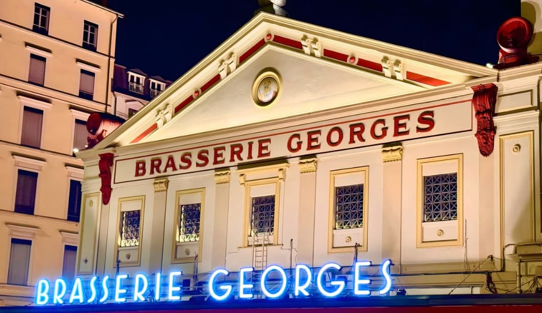 Façade illuminée de nuit avec enseignes néon Brasserie Georges rouge et doré