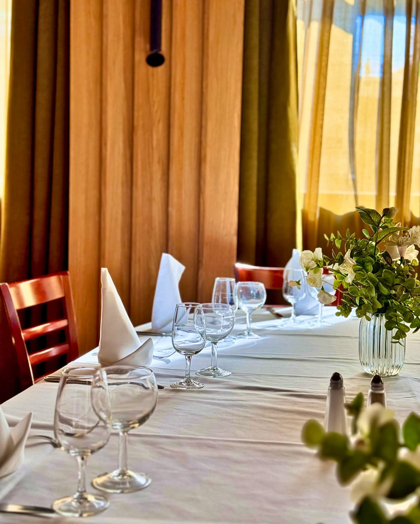 Table dressée avec bouquet de fleurs blanches devant rideaux dorés éclairés — Brasserie Georges
