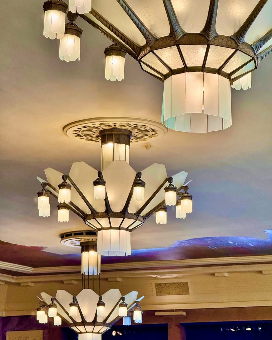Gros plan sur luminaires Art déco étagés au plafond, teintes bleu-violet — Brasserie Georges