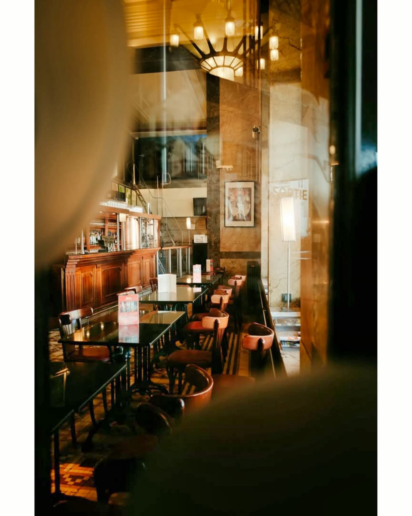 Long bar en bois avec tabourets, lumière chaude, enseigne visible au fond — Brasserie Georges