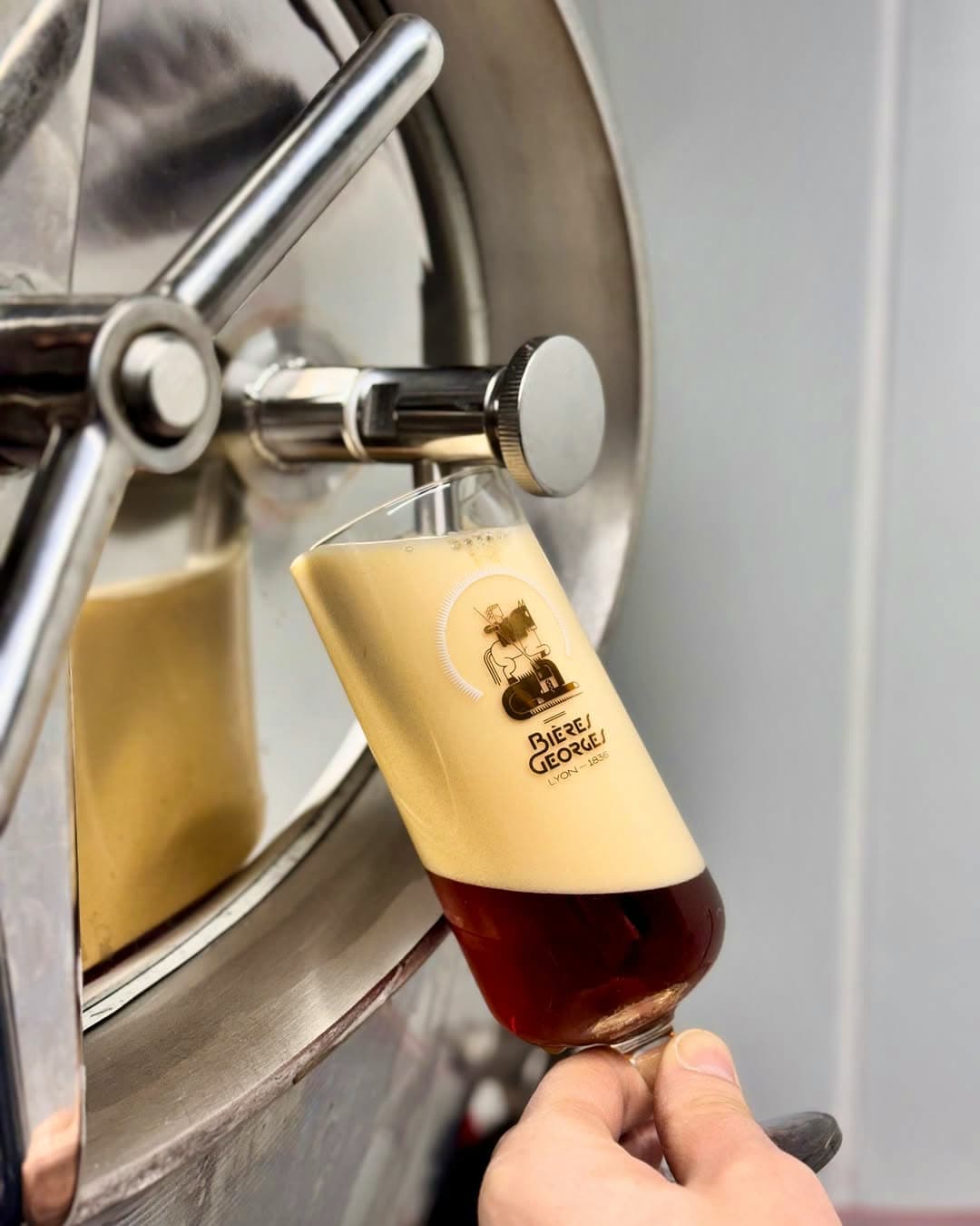 Main tenant un verre Bières Georges sous un robinet de soutirage inox — Brasserie Georges