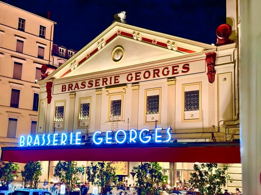 Façade illuminée de la Brasserie Georges de nuit avec enseigne néon
